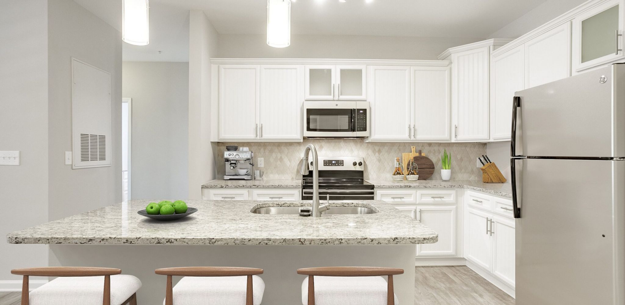 Hawthorne at Mirror Lake modern apartment kitchen with kitchen island, bar stools, espresso machine, and granite countertops